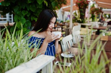 Fincan ile kafede masada oturan güzel esmer kız 