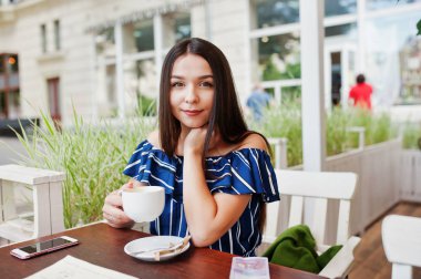 Fincan ile kafede masada oturan güzel esmer kız 