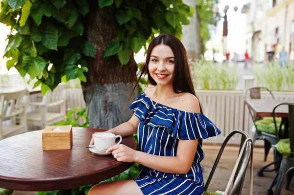 Fincan ile kafede masada oturan güzel esmer kız 