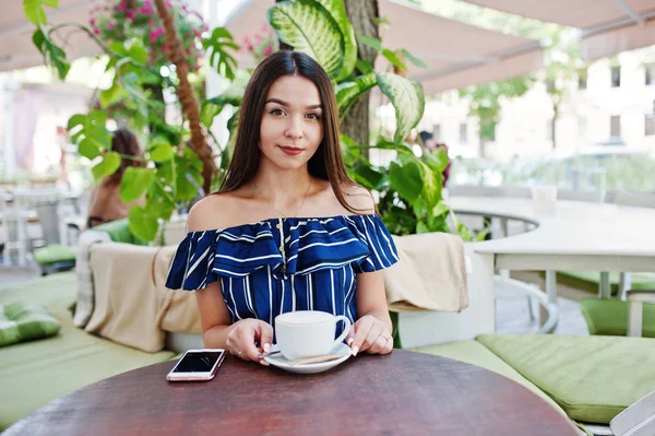 Fincan ile kafede masada oturan güzel esmer kız 