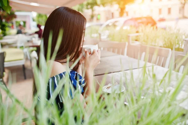 Fincan ile kafede masada oturan güzel esmer kız 