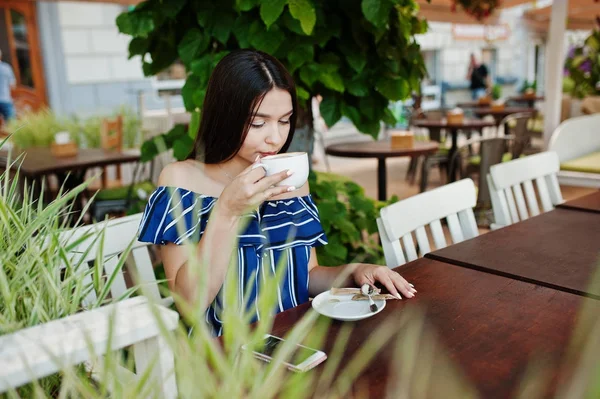 Fincan ile kafede masada oturan güzel esmer kız 