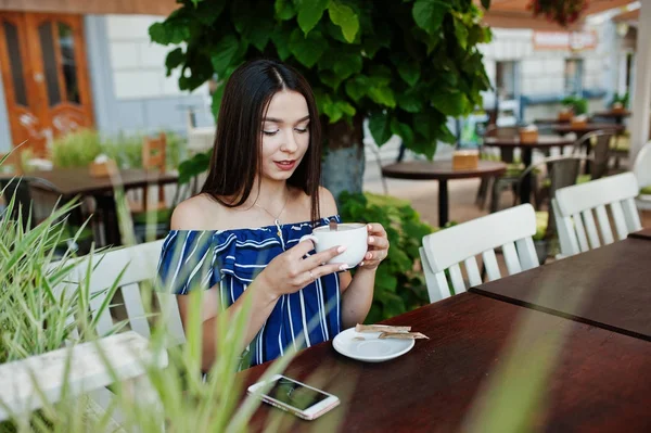 Fincan ile kafede masada oturan güzel esmer kız 