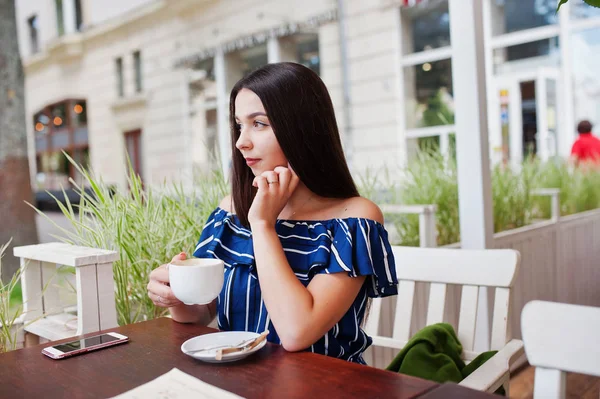 Fincan ile kafede masada oturan güzel esmer kız 