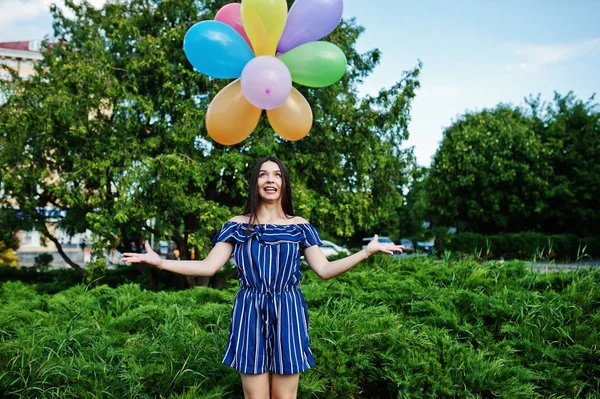 Prachtige brunette meisje op straat van de stad met ballonnen op handen. — Stockfoto