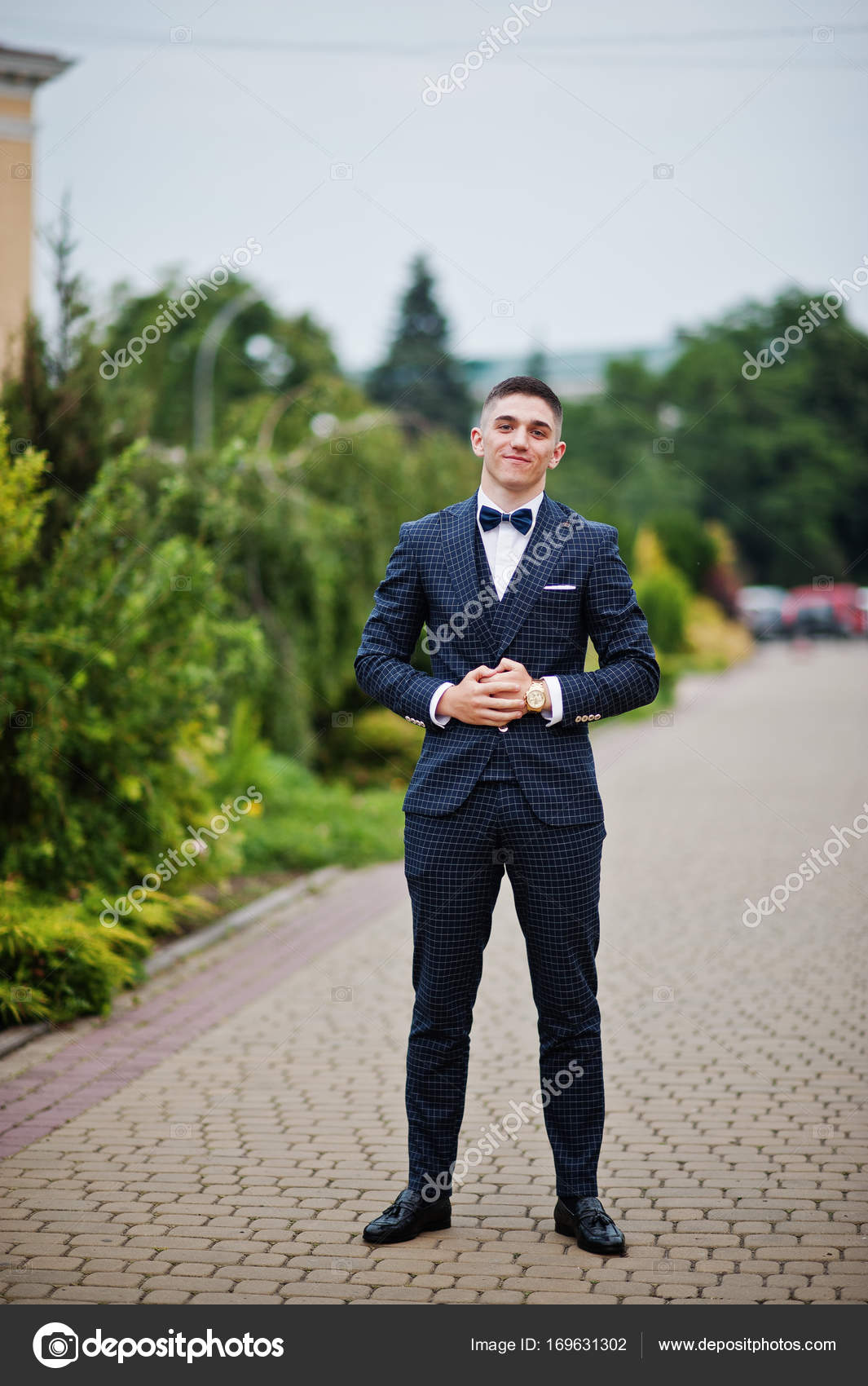 Handsome Bearded Man Or African American Groom In Elegant Suit Coat With  White Tie And Flower Boutonniere For Wedding Ceremony Poses On Sunny Summer  Day On Natural Background Stock Photo, Picture and
