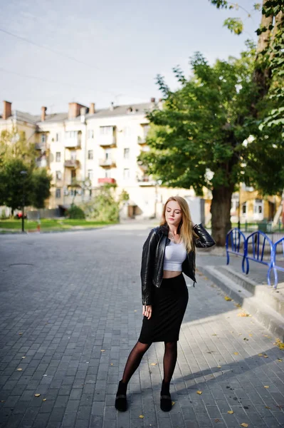 Elegante ropa de niña rubia en chaqueta de cuero negro posando en stree — Foto de Stock