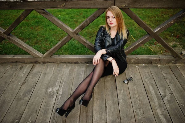Елегантна блондинка одягнена в чорну шкіряну куртку, позує на сходах — стокове фото