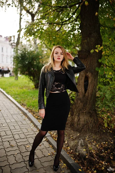 Elegante ropa de niña rubia en chaqueta de cuero negro posando en stree — Foto de Stock