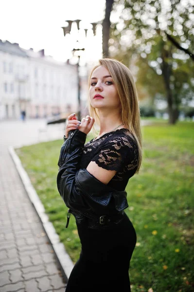 Elegantes blondes Mädchen in schwarzer Lederjacke posiert am Baum — Stockfoto