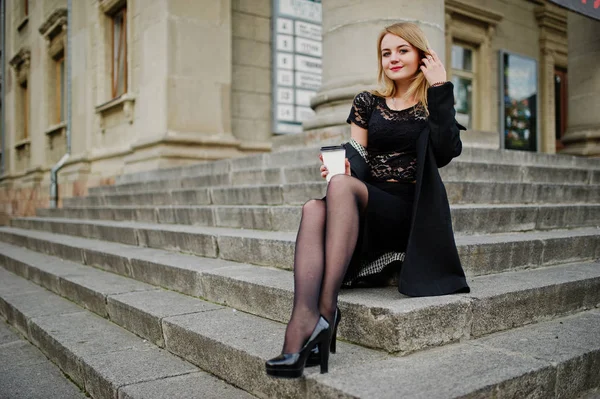 Elegante chica rubia llevar en negro posando en las calles de la ciudad, sentarse — Foto de Stock