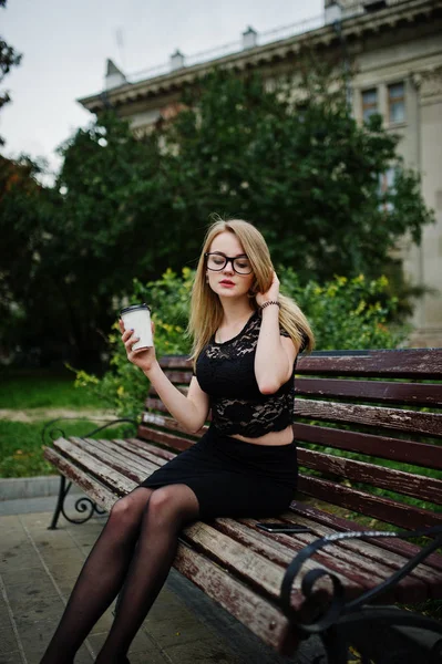 Elegante chica rubia llevar en negro posando en las calles de la ciudad, sentarse — Foto de Stock