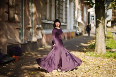 Sonbaharda mor elbise yetişkin esmer kadına düşmek arka plan.