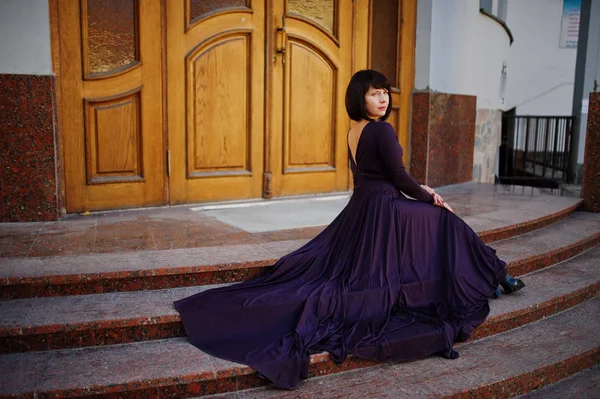 Mujer morena adulta en vestido violeta fondo viejas puertas de madera . — Foto de Stock