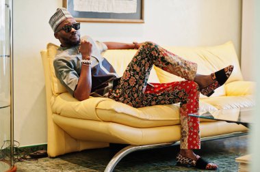 Onun daire, kanepede oturan zengin Afrika adam. Portresi 