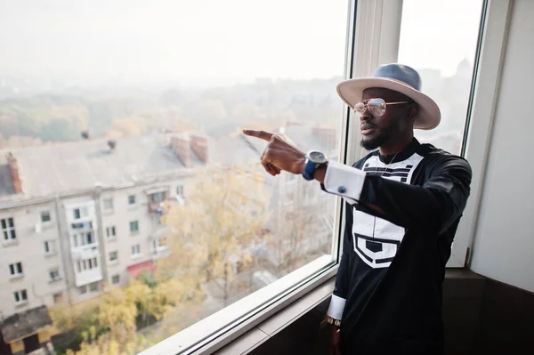 Un hombre africano rico mirando una ventana panorámica a su ático. P — Foto de Stock