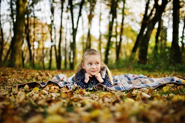 Little girl sitting on plaid at majestic autumn fall forest. — Stock Photo, Image