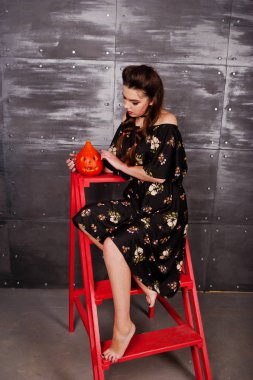 Kırmızı merdiveni ch üzerinde oturan parlak makyajlı elbiseli siyah kız