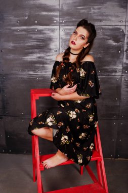 Kırmızı merdiveni ch üzerinde oturan parlak makyajlı elbiseli siyah kız