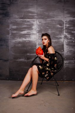 Parlak makyaj ve c üzerinde oturan kabak ile elbiseli siyah kız