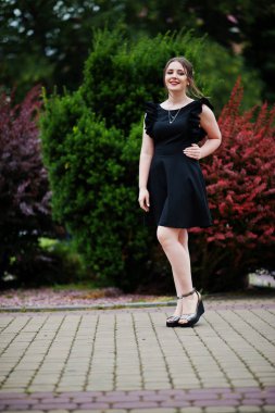 Üzerinde yürüyen siyah elbiseli güzel bir genç kız portresi 