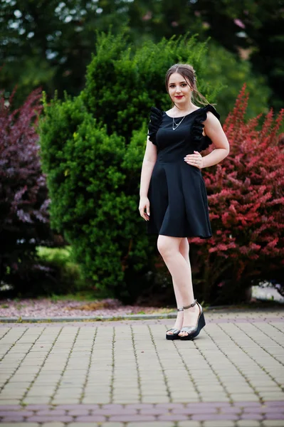 Retrato de uma jovem linda em vestido preto andando sobre o — Fotografia de Stock