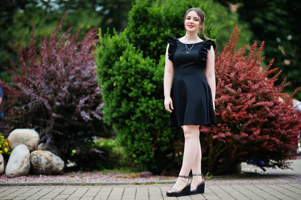 Porträtt av en vacker ung flicka i svart klänning gå på den — Stockfoto