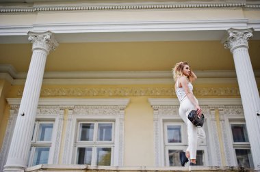 Şık kıvırcık sarışın model kız giymek beyaz eski karşı poz üzerinde