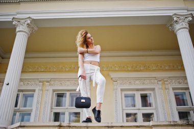 Şık kıvırcık sarışın model kız giymek beyaz eski karşı poz üzerinde