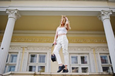 Şık kıvırcık sarışın model kız giymek beyaz eski karşı poz üzerinde