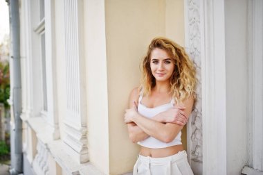 Şık kıvırcık sarışın model kız giymek beyaz eski karşı poz üzerinde