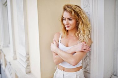 Şık kıvırcık sarışın model kız giymek beyaz eski karşı poz üzerinde