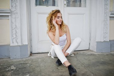 Şık kıvırcık sarışın model kız giymek beyaz eski karşı poz üzerinde