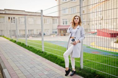 Şık kıvırcık sarışın model kız giymek beyaz fen karşı poz üzerinde