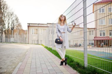 Şık kıvırcık sarışın model kız giymek beyaz fen karşı poz üzerinde