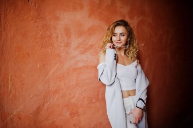 Şık kıvırcık sarışın model kız giymek beyaz ora karşı poz üzerinde