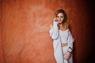 Şık kıvırcık sarışın model kız giymek beyaz ora karşı poz üzerinde