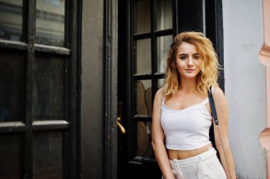 Şık kıvırcık sarışın model kız giymek beyaz eski karşı poz üzerinde