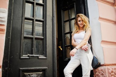 Şık kıvırcık sarışın model kız giymek beyaz eski karşı poz üzerinde