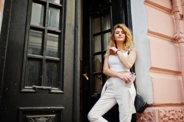 Şık kıvırcık sarışın model kız giymek beyaz eski karşı poz üzerinde