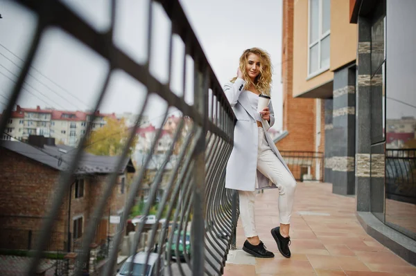 Elegante encaracolado loira modelo menina desgaste no branco com xícara de café — Fotografia de Stock