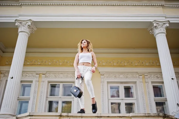 Şık kıvırcık sarışın model kız giymek beyaz eski karşı poz üzerinde