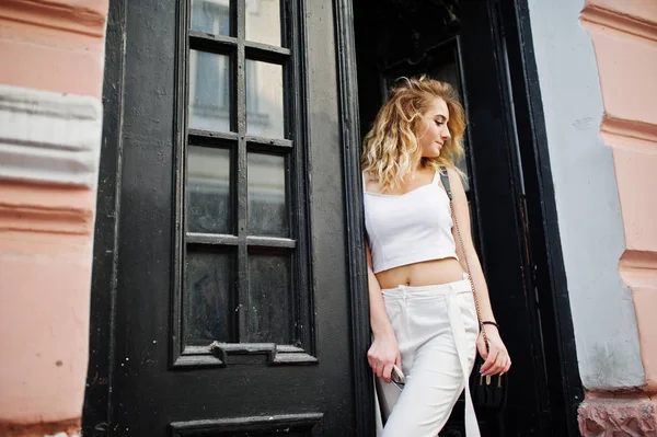 Şık kıvırcık sarışın model kız giymek beyaz eski karşı poz üzerinde