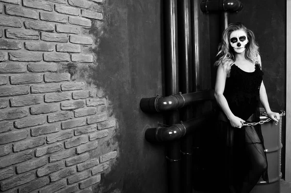 Хэллоуин череп макияж девушки носить в черном против сидя на ре — стоковое фото