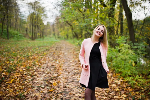 Jeune fille blonde au manteau rose posé sur le parc d'automne . — Photo