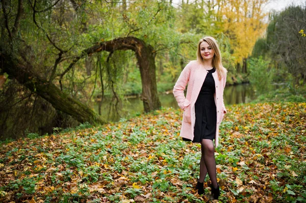 Chica rubia joven en el abrigo rosa posado en el parque de otoño . —  Fotos de Stock