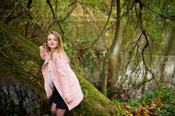 Junges blondes Mädchen im rosafarbenen Mantel posierte im Herbstpark. — Stockfoto