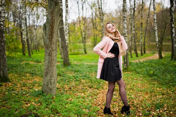 Junges blondes Mädchen im rosafarbenen Mantel posierte im Herbstpark. — Stockfoto