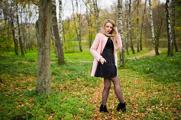 Chica rubia joven en el abrigo rosa posado en el parque de otoño . — Foto de Stock