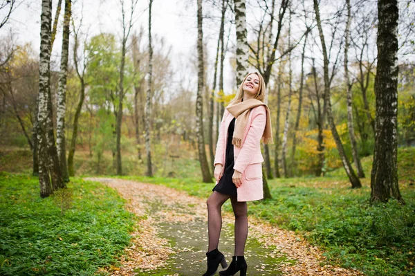 Menina loira jovem no casaco rosa posado no parque de outono . — Fotografia de Stock